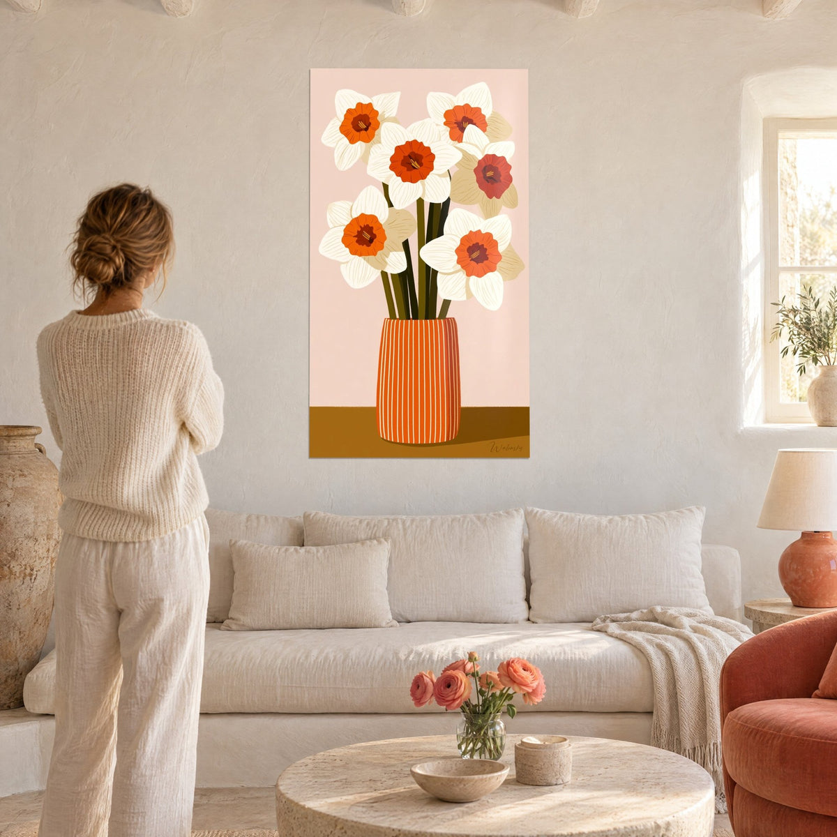 Gemälde Strauß weißer Narzissen mit orangefarbener Mitte in einer gestreiften Vase, puderrosa Hintergrund, über einem Sofa in einem hellen Wohnzimmer