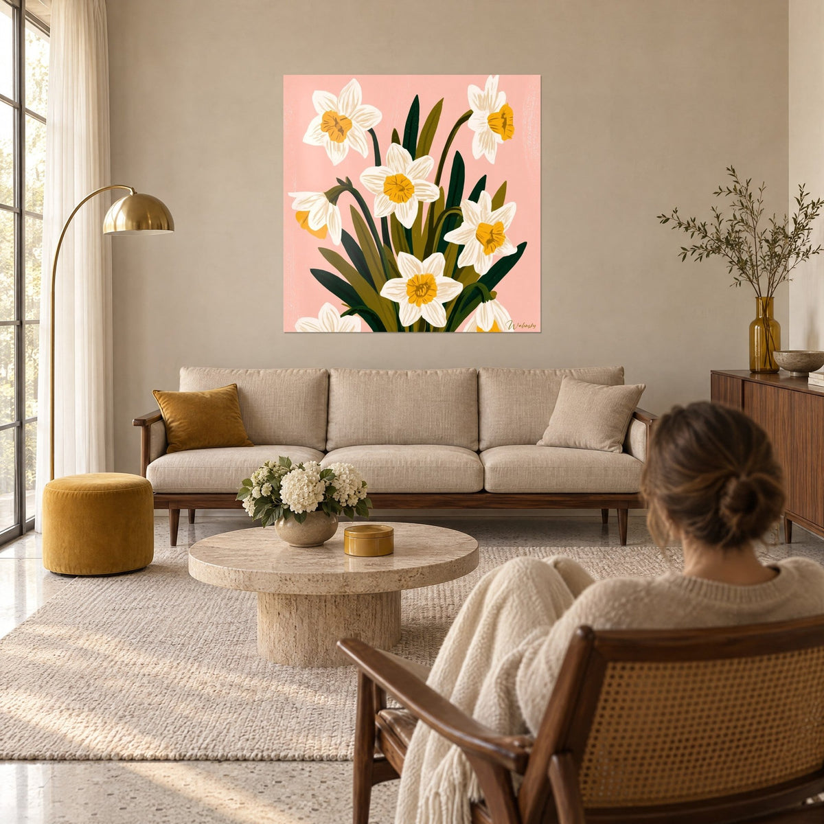 Quadro con narcisi bianchi dal cuore giallo oro su sfondo rosa, foglie verde abete, appeso sopra un divano in un soggiorno luminoso