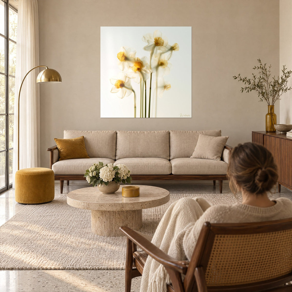 Wall art with daffodils, translucent white petals and golden-yellow centres, green stems, above a sofa in a bright living room