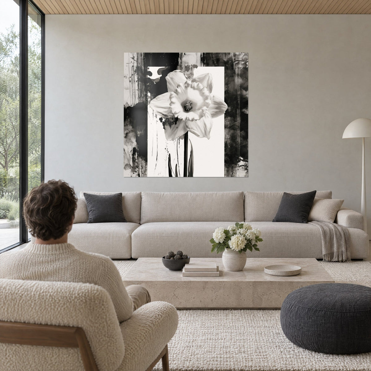 Wall art monochrome daffodil with ivory frilled petals, splattered black ink background, hung above a sofa in a bright living room