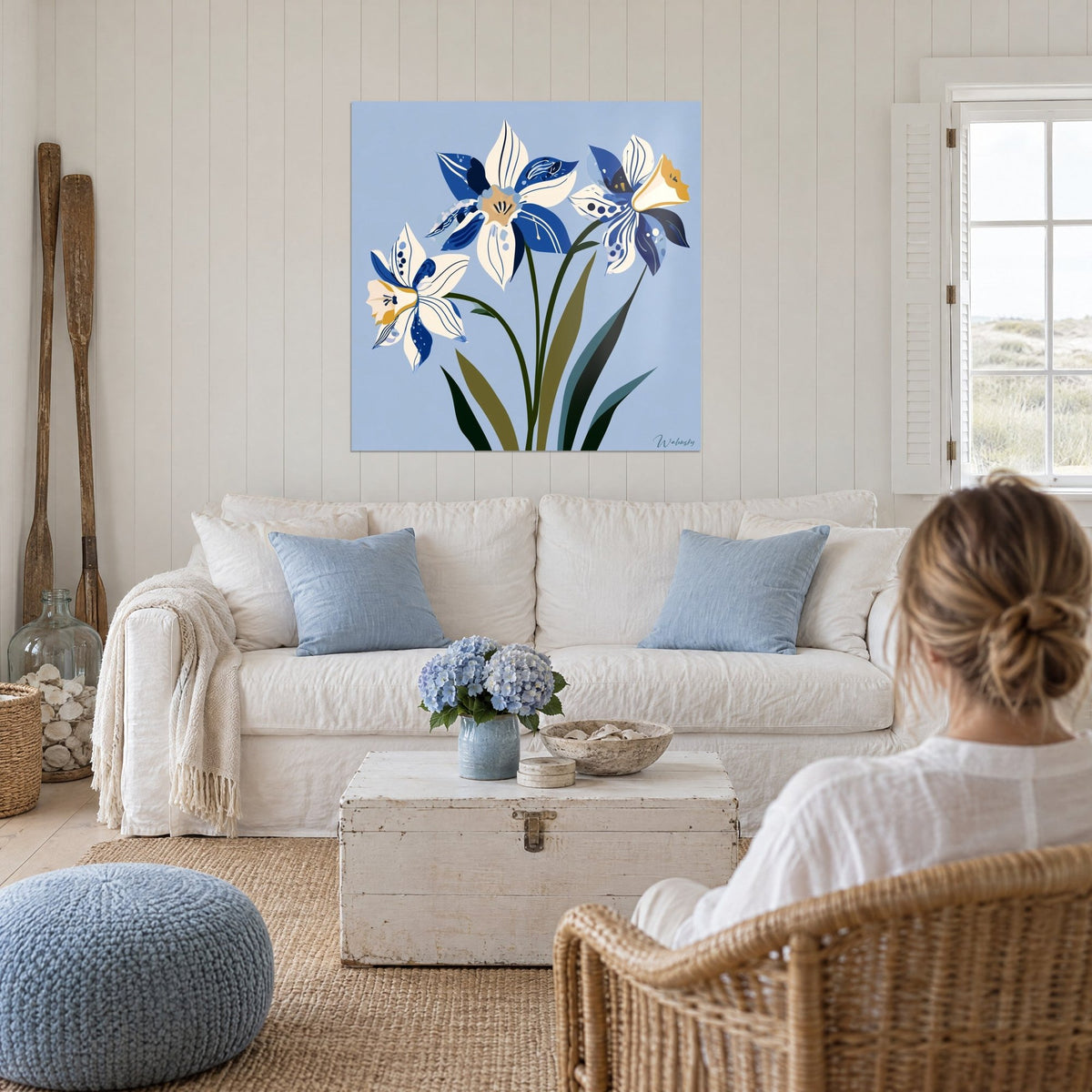 Gemälde drei Narzissen in Marineblau und Elfenbein auf himmelblauem Grund, zwei Frauen von hinten, über einem Sofa in einem hellen Wohnzimmer