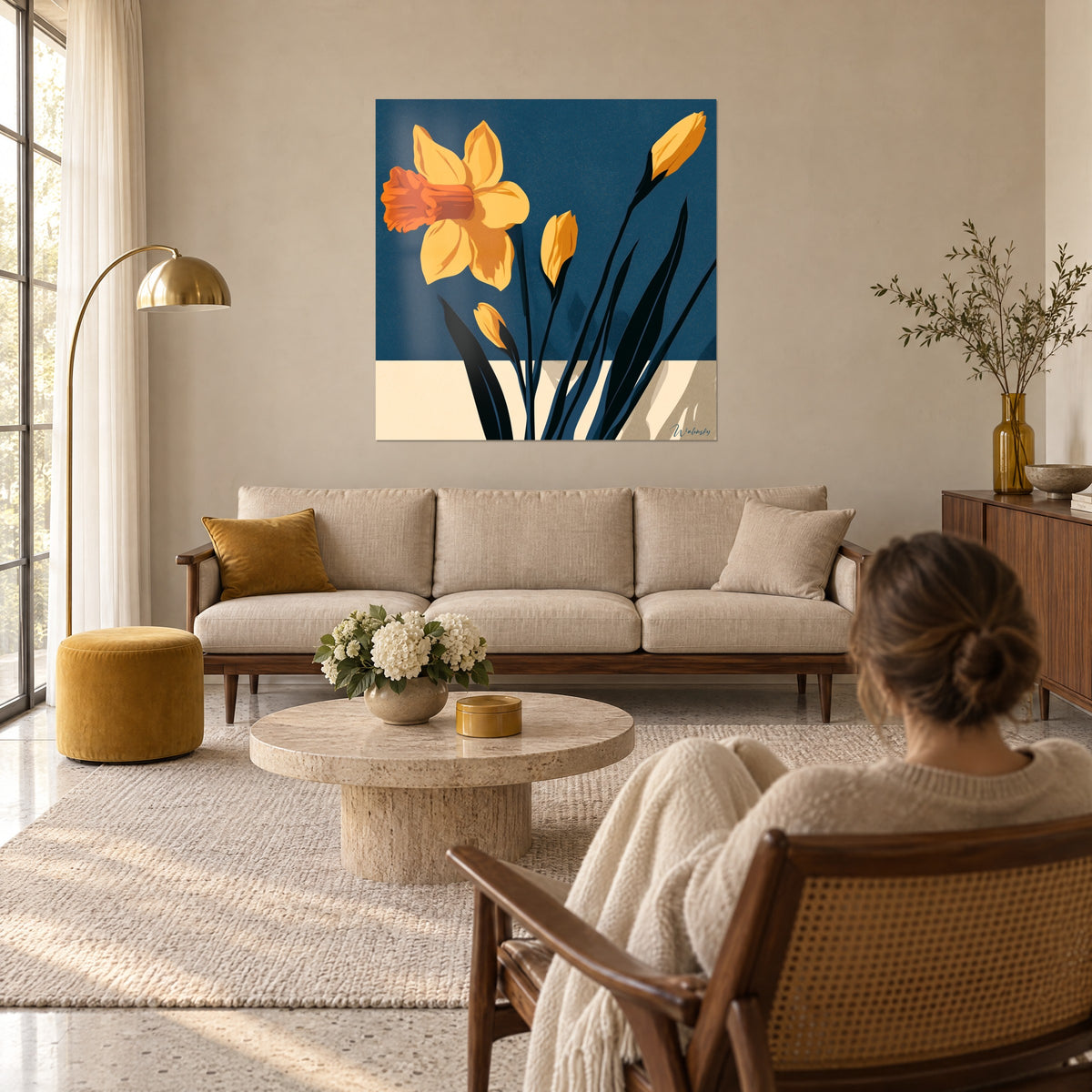 Tableau jonquille jaune safran à cœur orange sur fond bleu marine, une femme de dos, au-dessus d'un canapé dans un salon lumineux