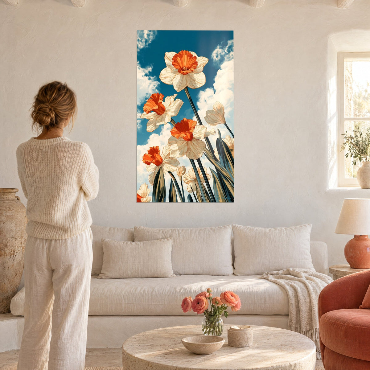 Quadro narcisi avorio con cuore arancione vivo contro un cielo blu petrolio, donna di spalle, sopra un divano in un soggiorno luminoso