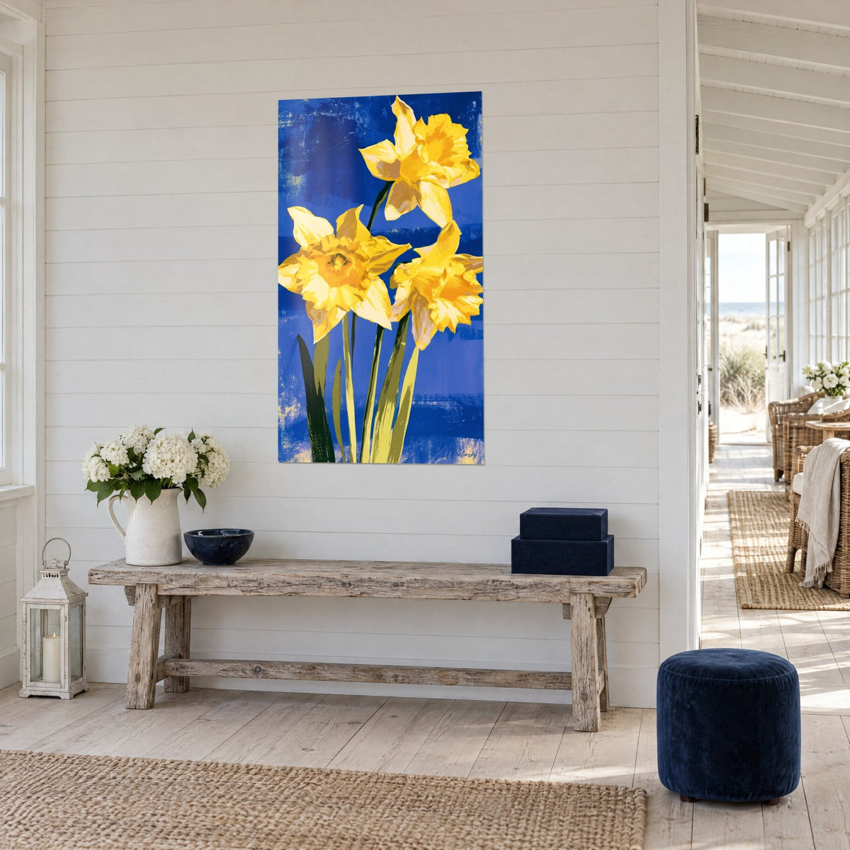 Wall art three yellow daffodils with olive green stems on royal blue, hung beside a wooden console, seaside setting