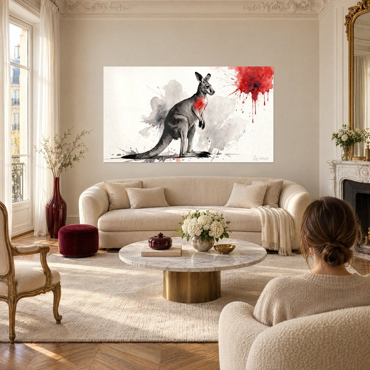 Tableau marsupial gris debout, éclaboussure rouge vif en haut à droite, femme de dos, au-dessus d'un canapé dans un salon lumineux