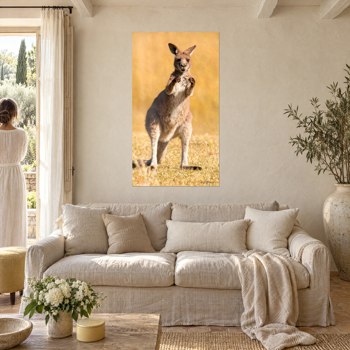Wall art standing grey kangaroo, forepaws raised, on a golden grass background, above a sofa in a bright living room