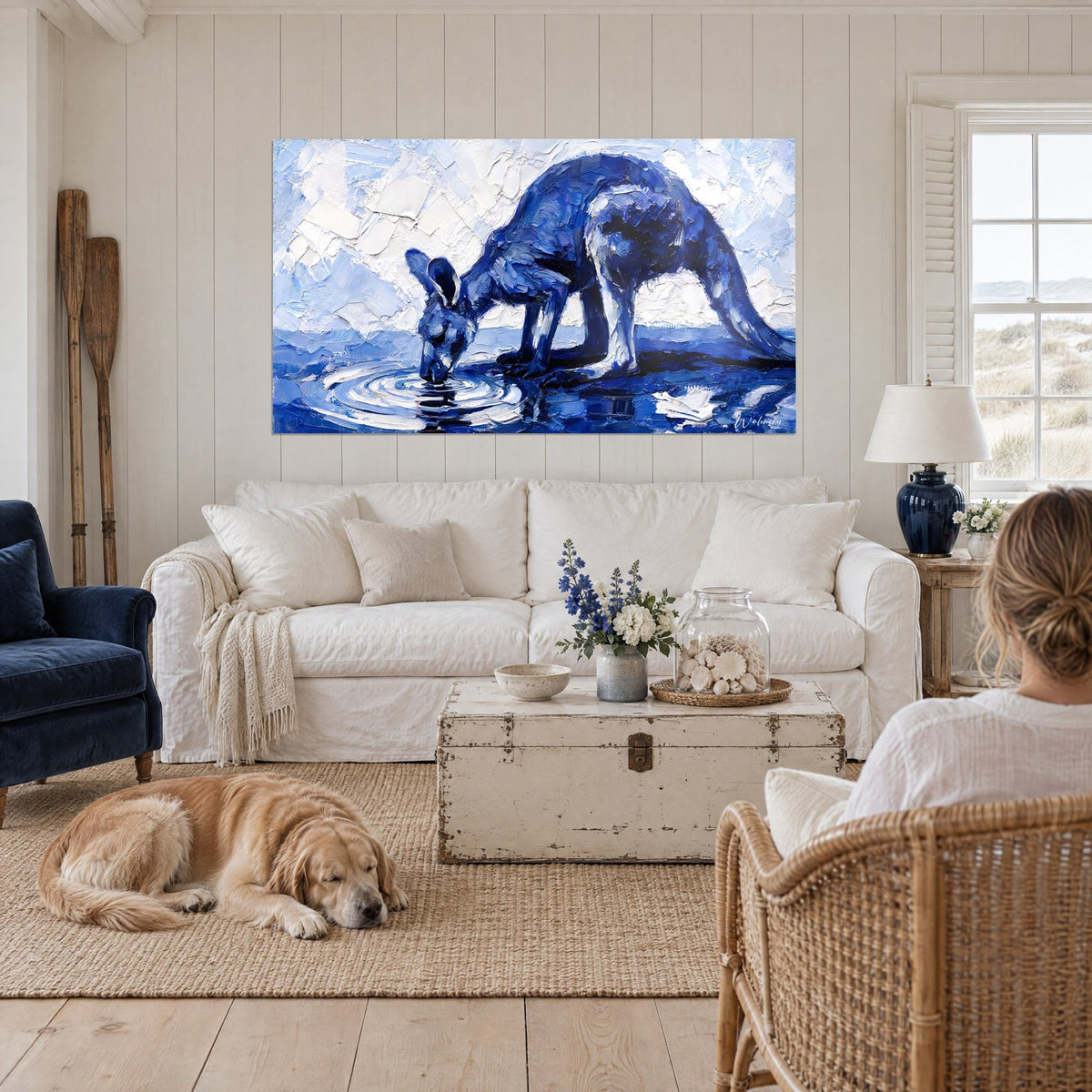 Tableau kangourou indigo penché sur l'eau, ciel blanc en pâte épaisse, retriever couché, au-dessus d'un canapé dans un salon lumineux