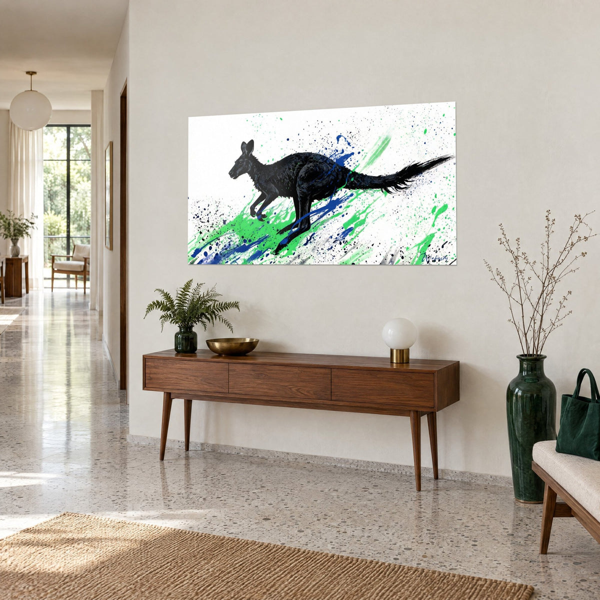 Tableau marsupial d'encre noire lancé en pleine course, traînées vert vif et bleu roi, sur un mur beige près d'un buffet