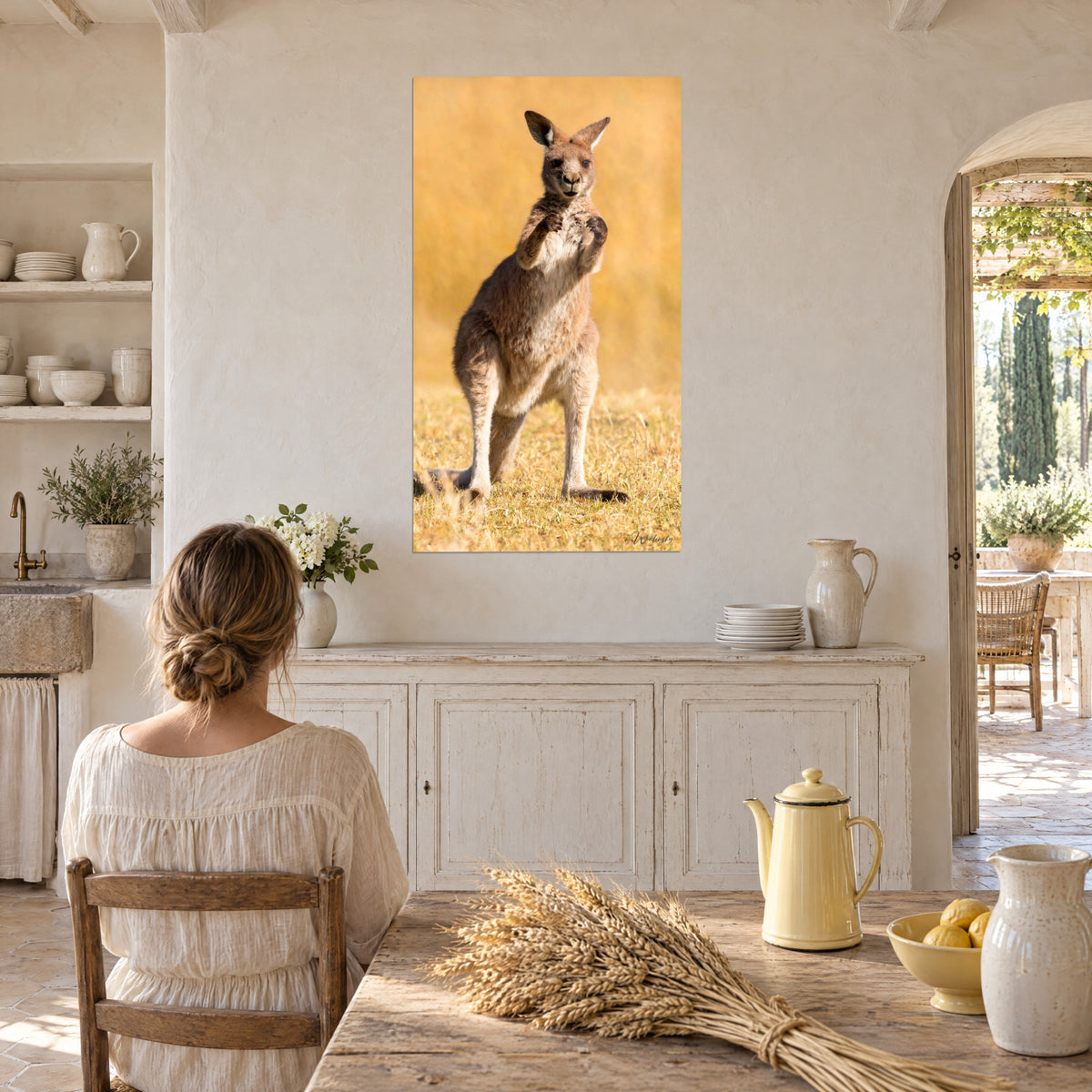 Wall art red kangaroo with an attentive gaze, fists raised, amber dry grass, on the wall of a vaulted kitchen in white stone