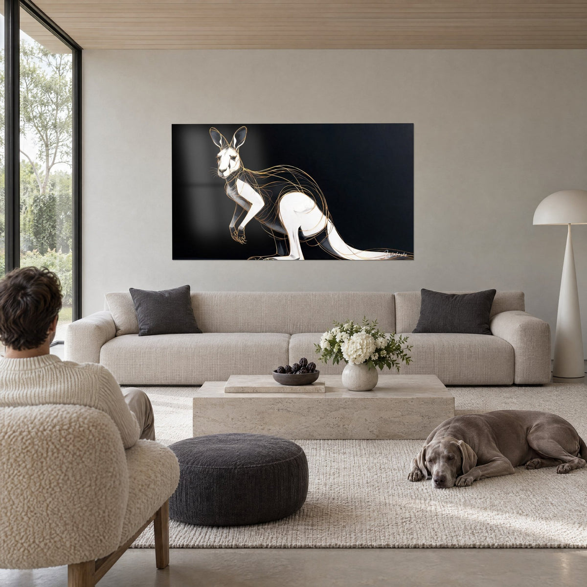 Schilderij Wit kangoeroe omlijnd door gouden filamenten op zwarte achtergrond, twee personen van achteren en een Weimaraner, boven een bank in een lichte woonkamer