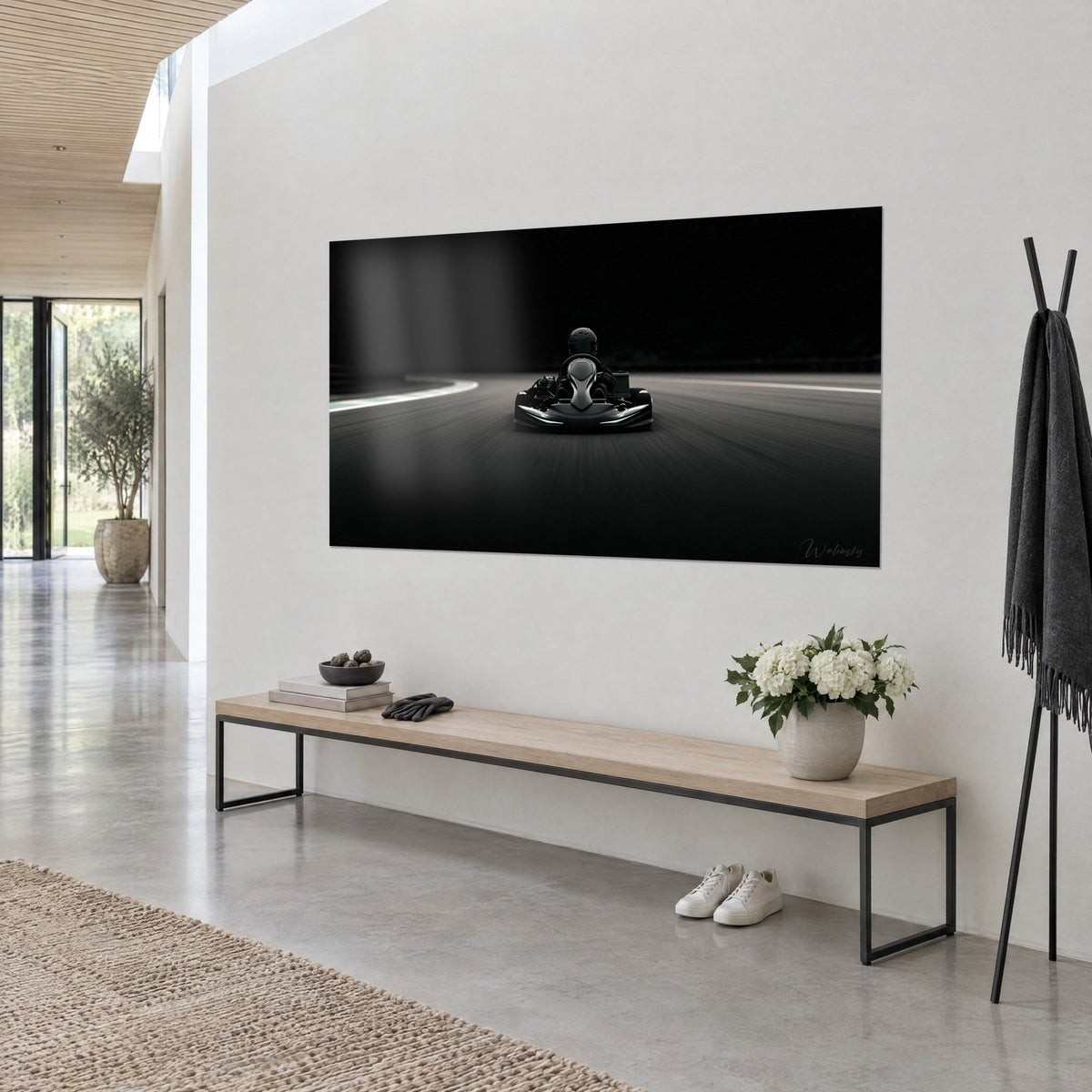 Tableau pilote casqué en bolide de karting sur bitume anthracite, liseré blanc au virage, au mur d'une entrée en trois-quarts