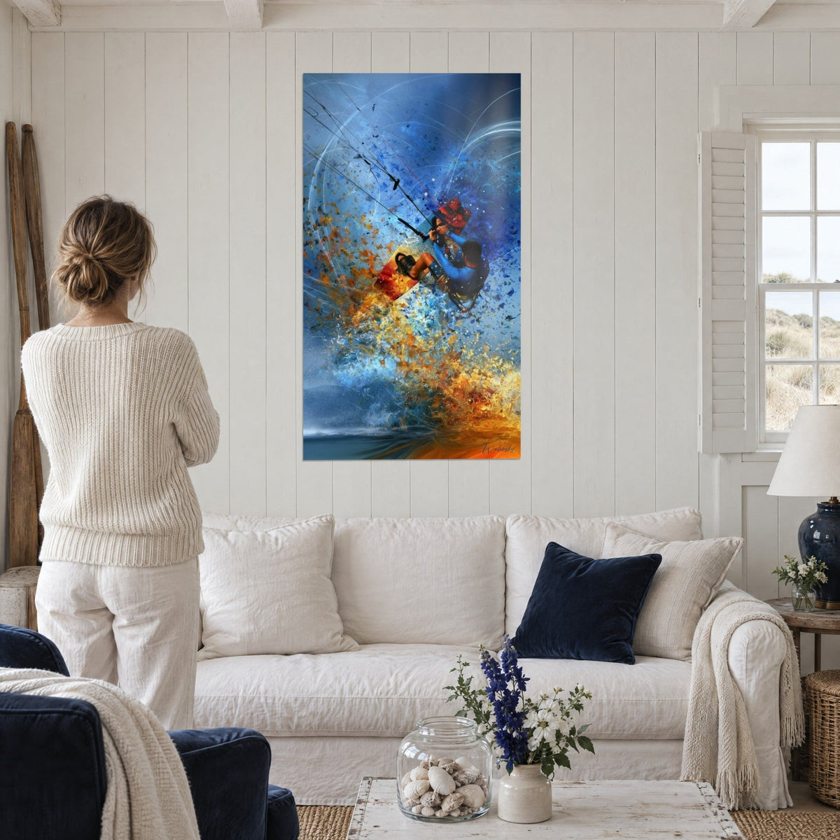 Tableau kitesurfeur en combinaison bleue, bris de fragments orange et azur, au-dessus d'un canapé dans un salon lumineux