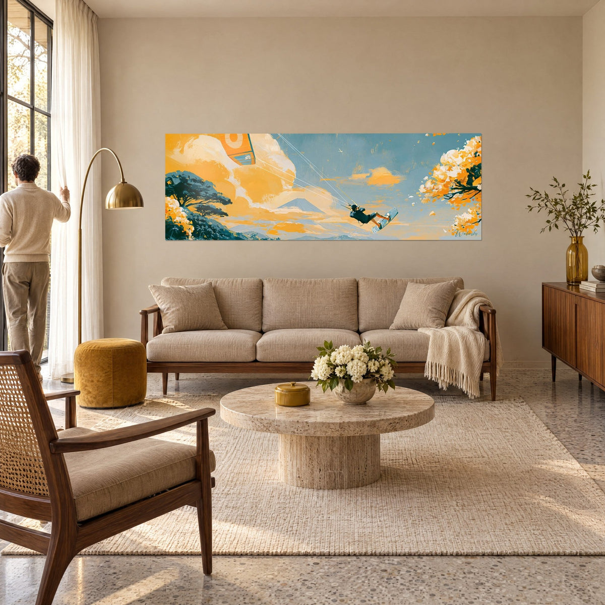 Wall art kitesurfer in a black wetsuit stretched beneath an orange kite, blue volcano and golden clouds, above a sofa in a bright living room
