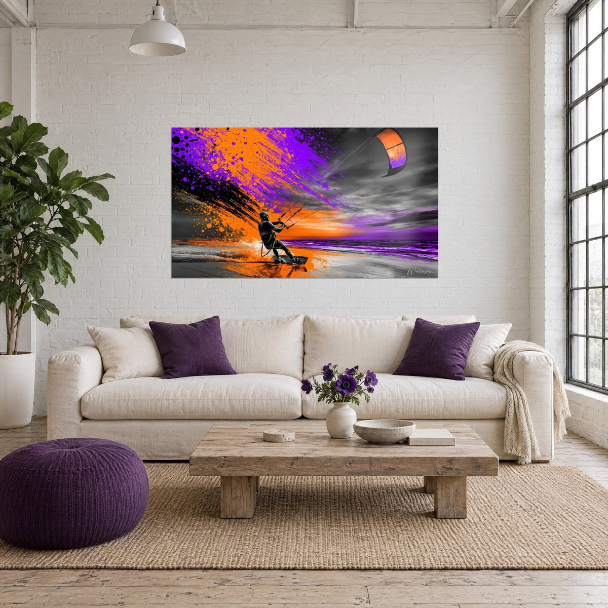 Tableau kitesurfeur tirant sa voile orange, éclaboussures violettes et orangées sur ciel gris, au-dessus d'un canapé dans un salon lumineux