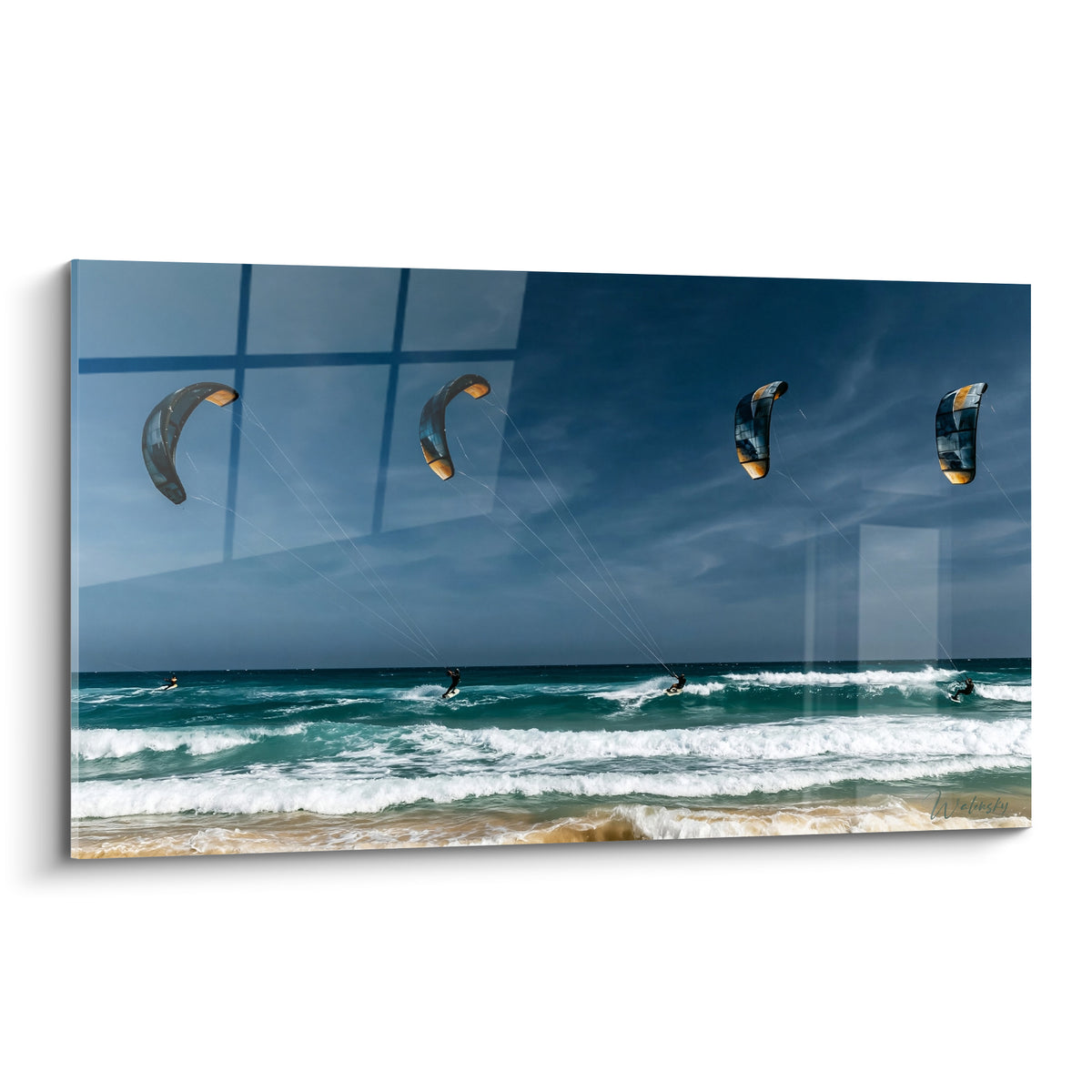 Quatre voiles de kite surf bleues et ocre survolant une mer turquoise écumée sous ciel marine