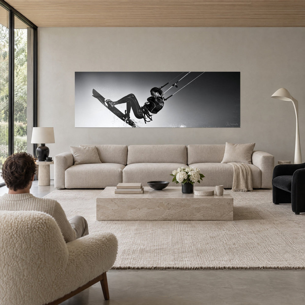 Gemälde Kitesurferin im Sprung, schwarzer Neoprenanzug, Board auf perlgrauem Hintergrund, über einem Sofa in einem hellen Wohnzimmer