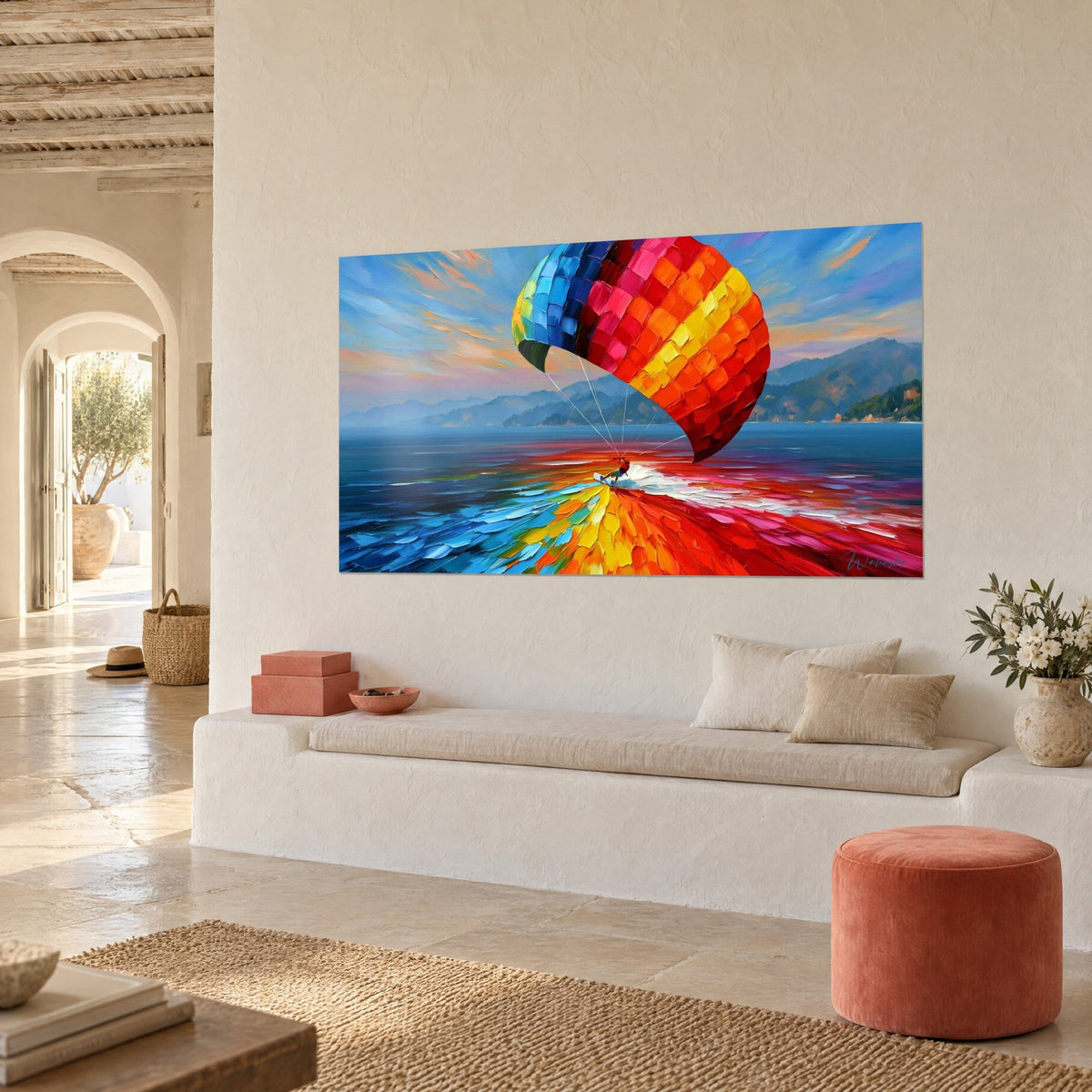 Tableau aile de kite aux carrés orange et jaune, mer turquoise et montagnes bleutées, sur un mur chaux près d'une alcôve
