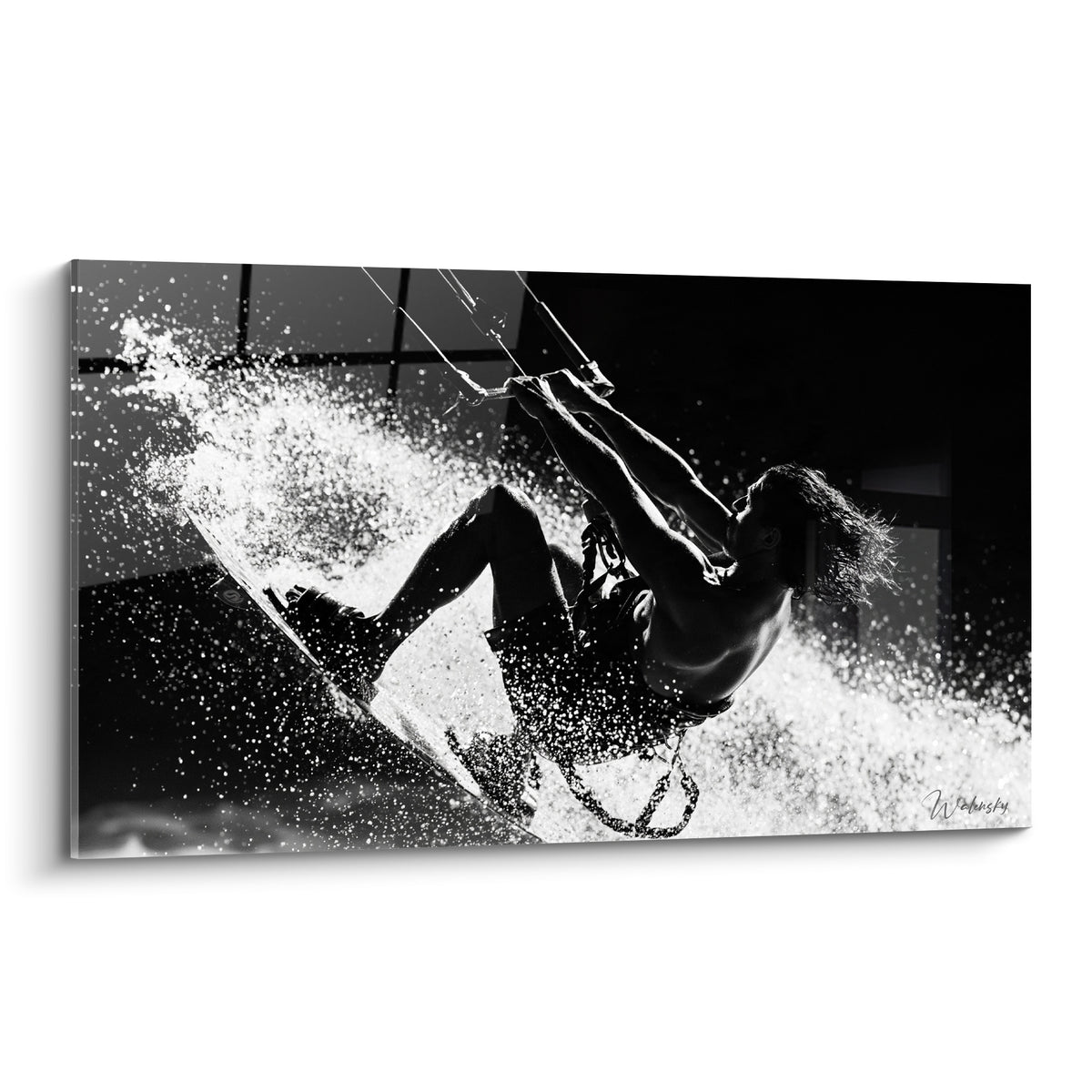 Kitesurfeur noir et blanc suspendu dans une gerbe d'eau argentée et anthracite éclatante