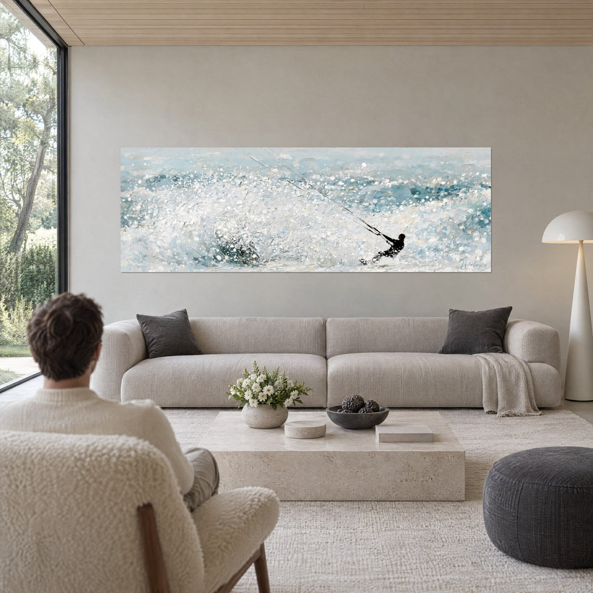 Tableau kitesurfeur en combinaison noire sur gerbes d'écume blanche et bleu glacier, au-dessus d'un canapé dans un salon lumineux