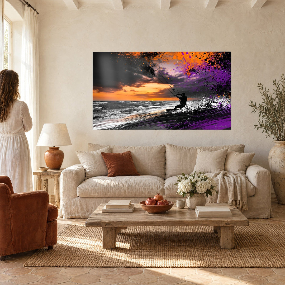 Tableau kitesurfeur en silhouette noire tenant ses lignes, ciel orange et éclaboussures violettes, au-dessus d'un canapé dans un salon lumineux