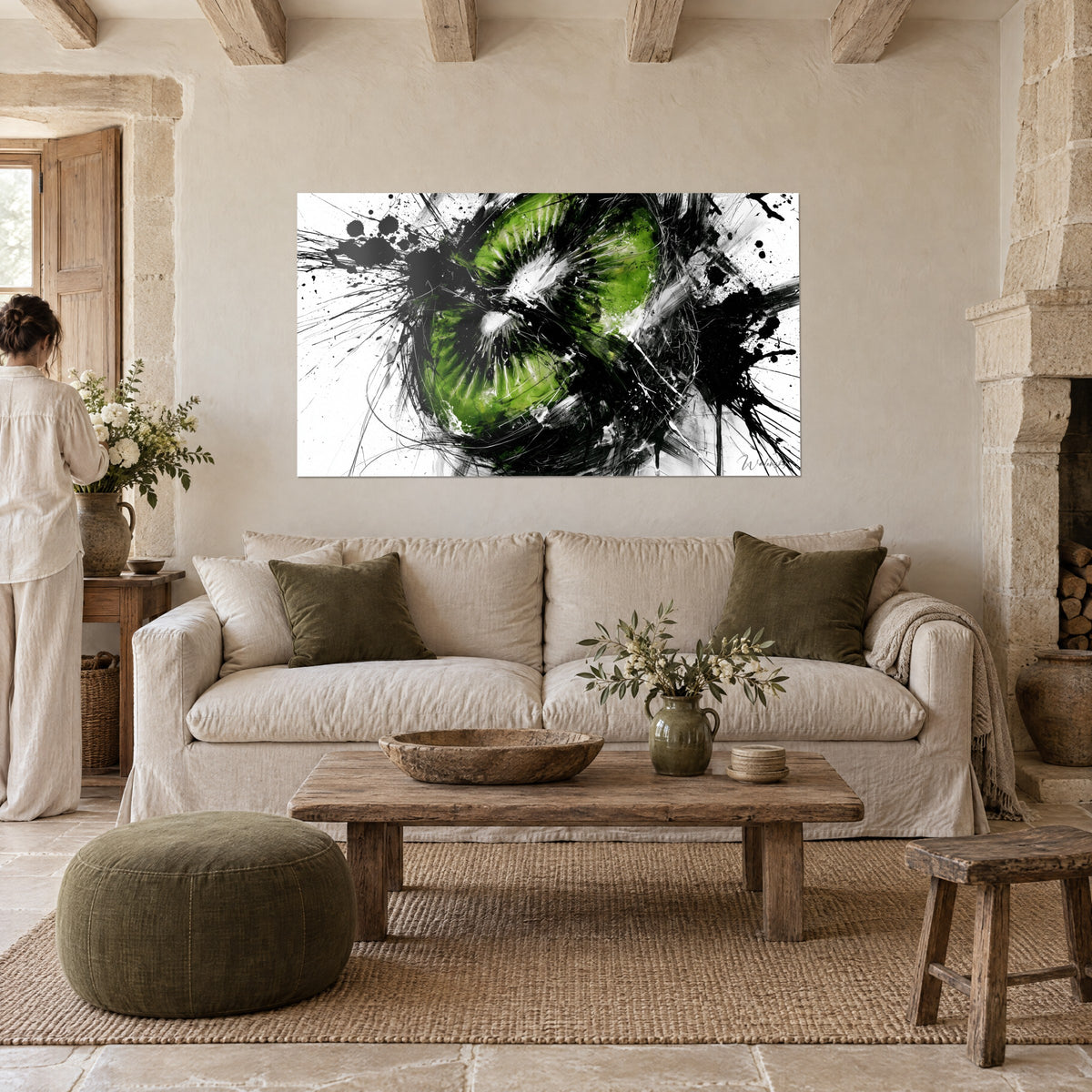 Tableau kiwi coupé en deux, chair vert vif et projections d'encre noire, personne de dos, au-dessus d'un canapé dans un salon lumineux