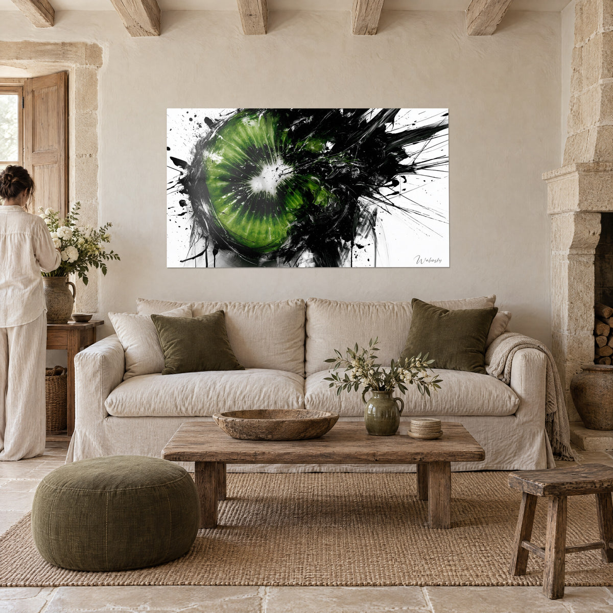 Tableau kiwi tranché au cœur crème, chair verte et éclaboussures noires, femme de dos, au-dessus d'un canapé dans un salon lumineux