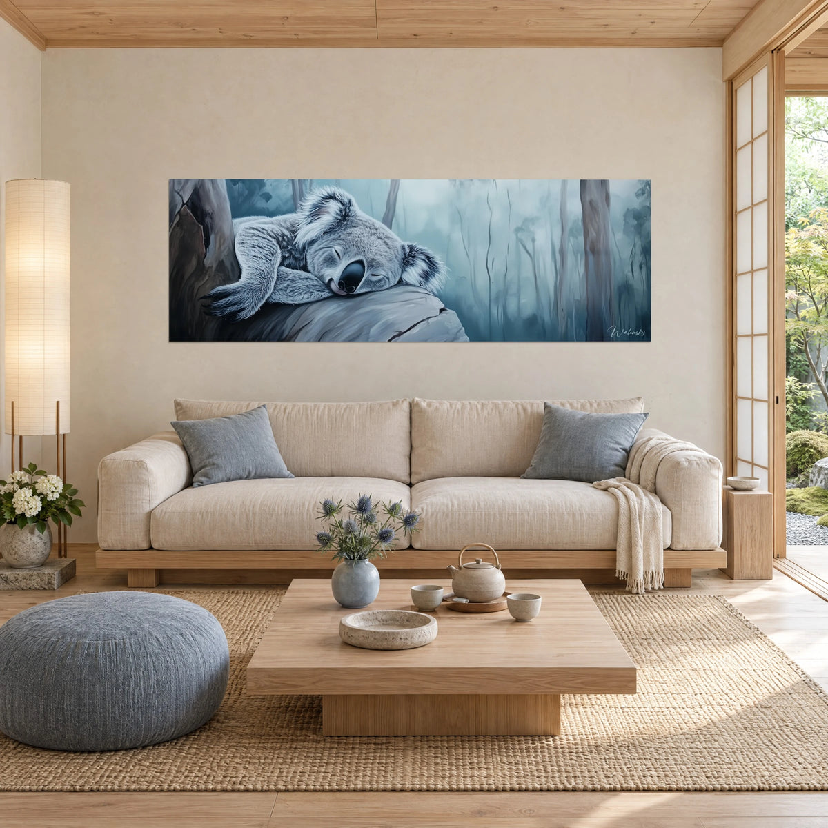 Wall art of a sleeping koala in the mist, silvery grey fur on a petrol blue background, above a sofa in a bright living room