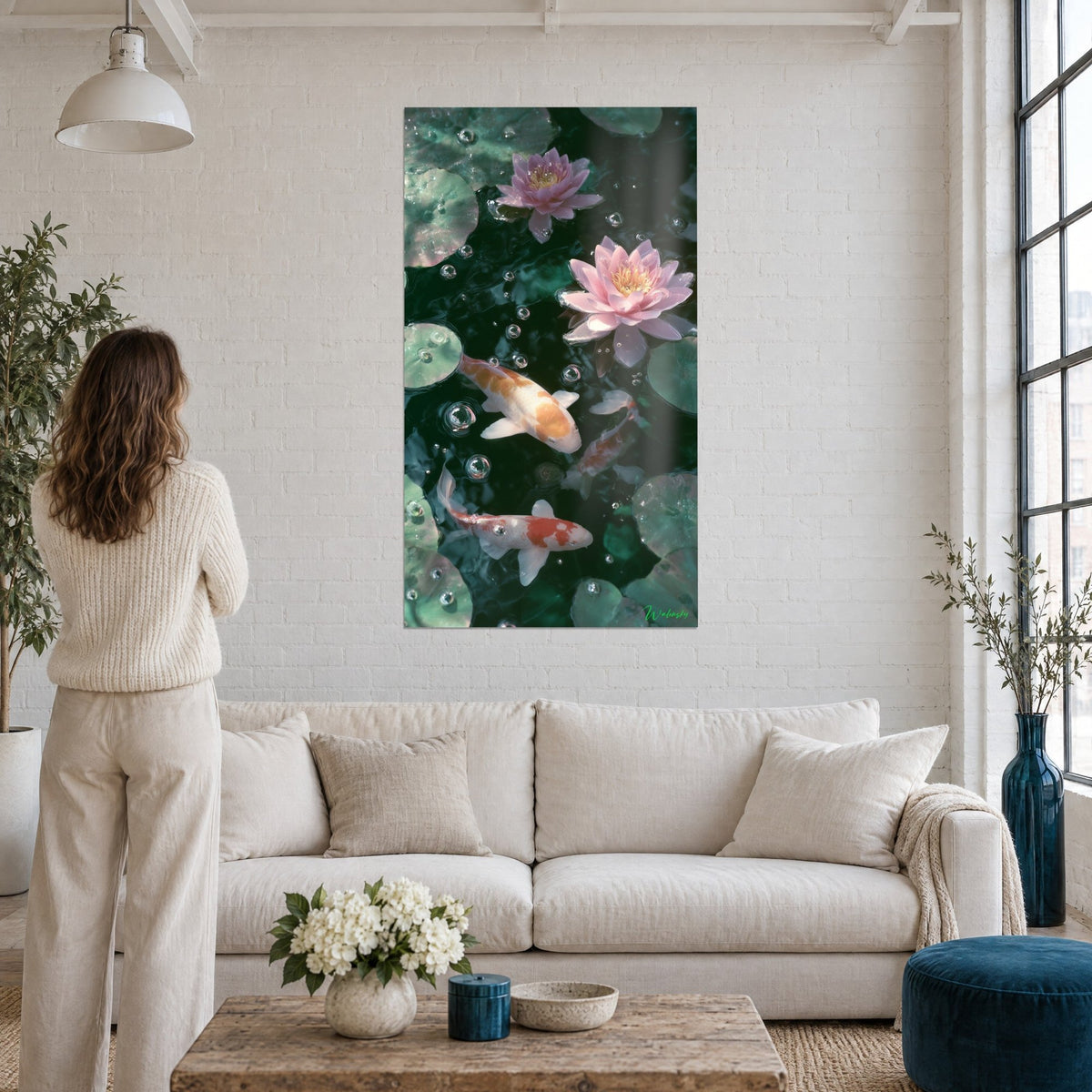 Quadro carpe koi arancioni e bianche che scivolano tra ninfee rosa, acqua verde smeraldo, donna di schiena, sopra un divano in un soggiorno luminoso