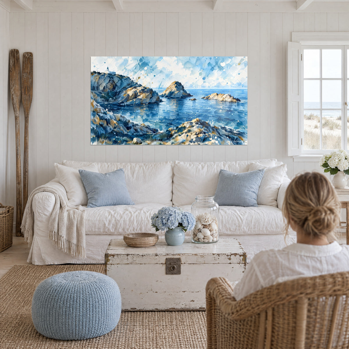 Quadro di costa rocciosa con scogliere blu acciaio e ocra, faro bianco sulla falesia, sopra un divano in un soggiorno luminoso