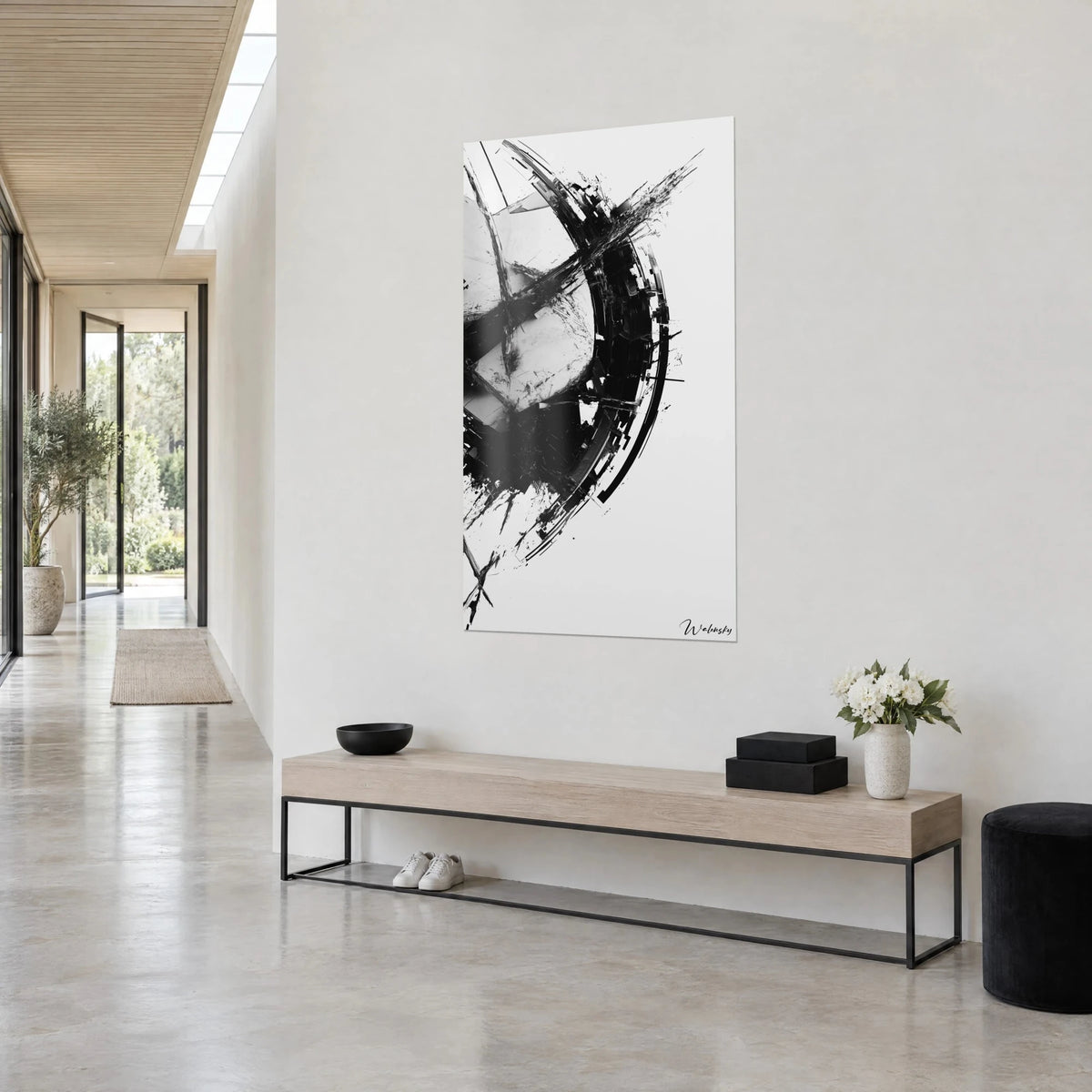 Wall art with a fractured circle in black ink and pearl grey, splashes rising upward, three-quarter view in an architect's house hallway