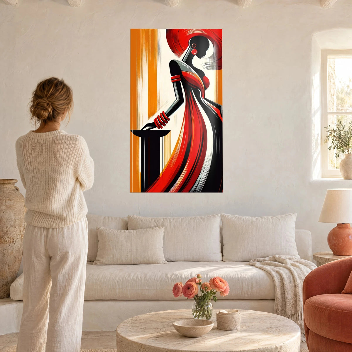Tableau silhouette noire drapée de rouge vif, boucle d'oreille ronde, fond orange, au-dessus d'un canapé dans un salon lumineux