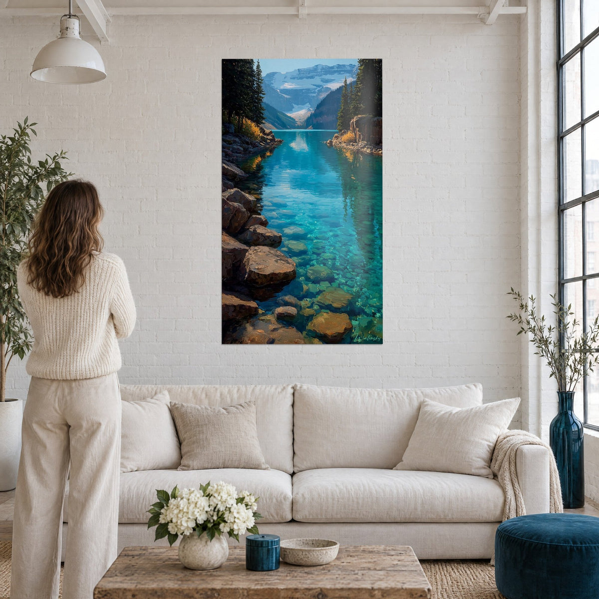 Tableau lac de montagne aux eaux turquoise et pierres ocre, glacier au fond, femme de dos, au-dessus d'un canapé dans un salon lumineux