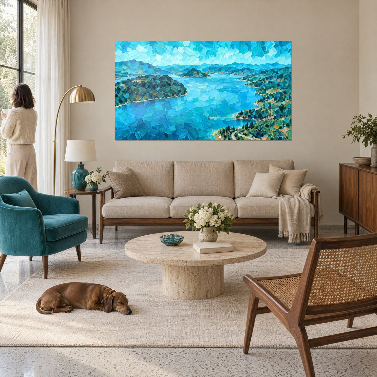 Gemälde türkisfarbener, sich schlängelnder See zwischen grünen Hügeln, blaue und ockerfarbene Spachtelstriche, über einem Sofa in einem hellen Wohnzimmer