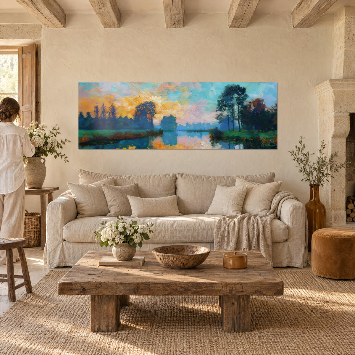 Tableau paysage lacustre au couchant, ciel doré et rose sur eau turquoise, pins sombres, au-dessus d'un canapé dans un salon lumineux