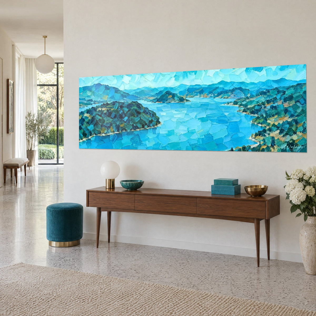 Cuadro bahía azur y penínsulas cubiertas de pinos, toques de azul cielo y ocre, sobre una pared beige junto a una consola