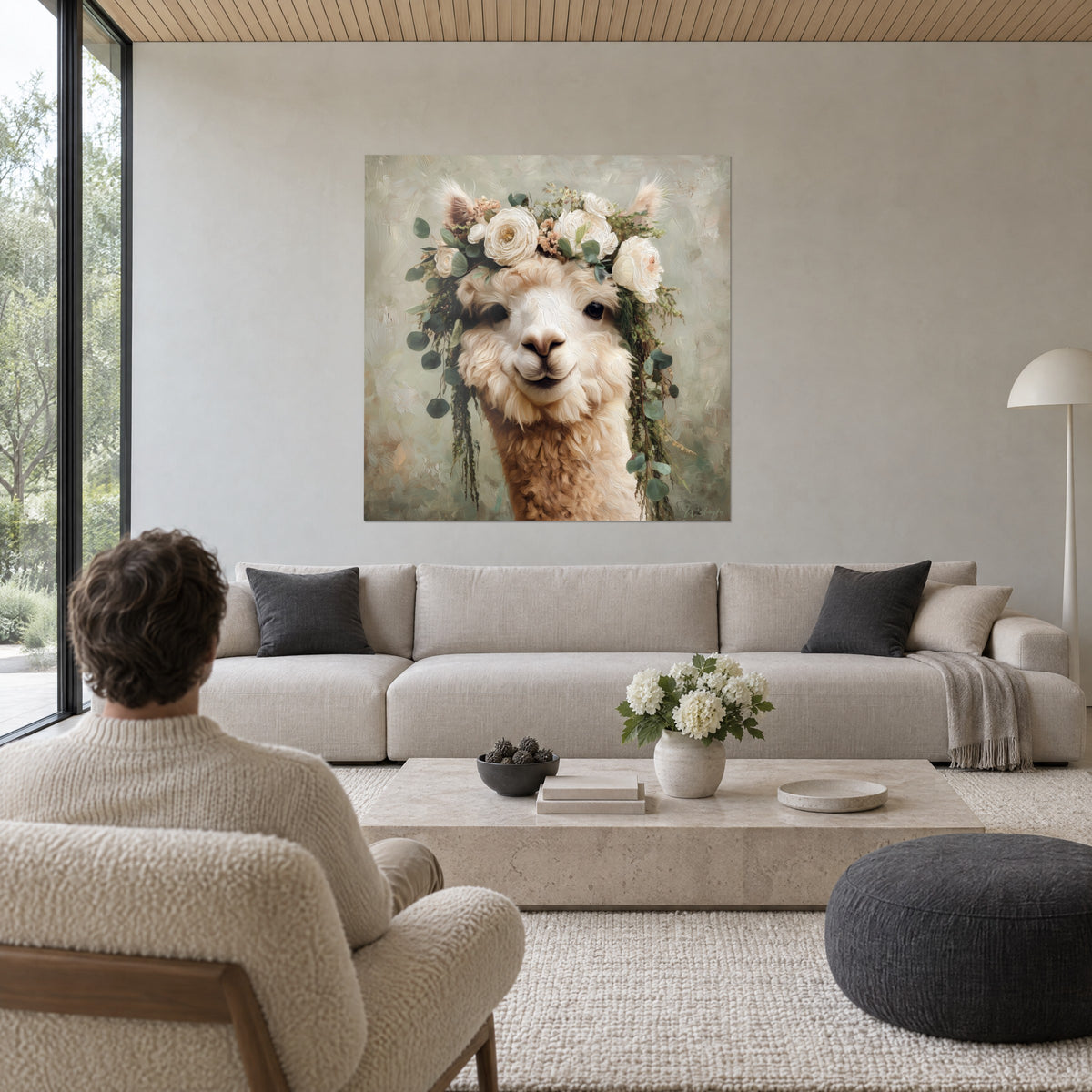 Schilderij van een crèmekleurige alpaca gekroond met witte rozen en saliegroene eucalyptus, zachte blik, boven een bank in een lichte woonkamer