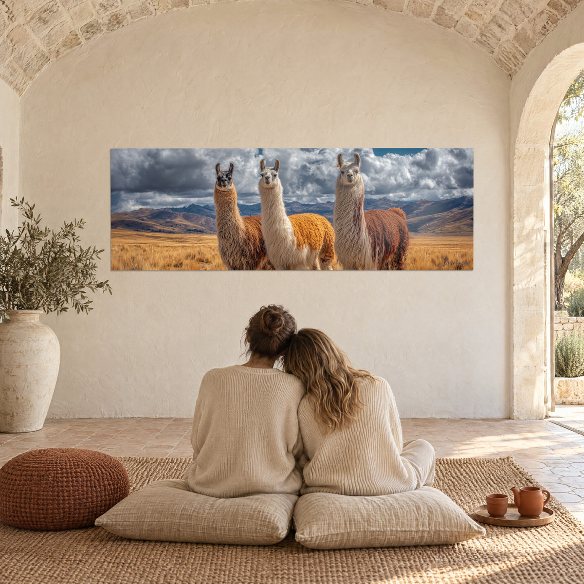 Cuadro llamas curiosas de orejas erguidas, lana roja y blanca, cielo nublado, frente a una pareja de espaldas sobre cojines