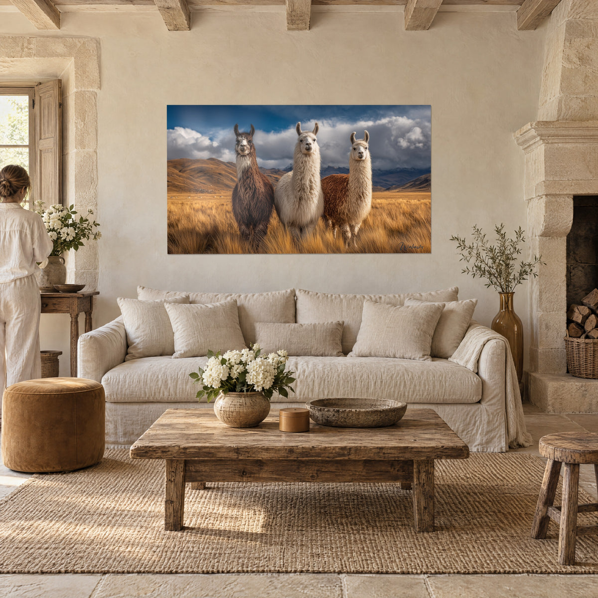 Gemälde dreier brauner und cremefarbener Lamas im goldenen Gras, stürmischer blauer Himmel, eine Frau von hinten über einem Sofa in einem hellen Wohnzimmer