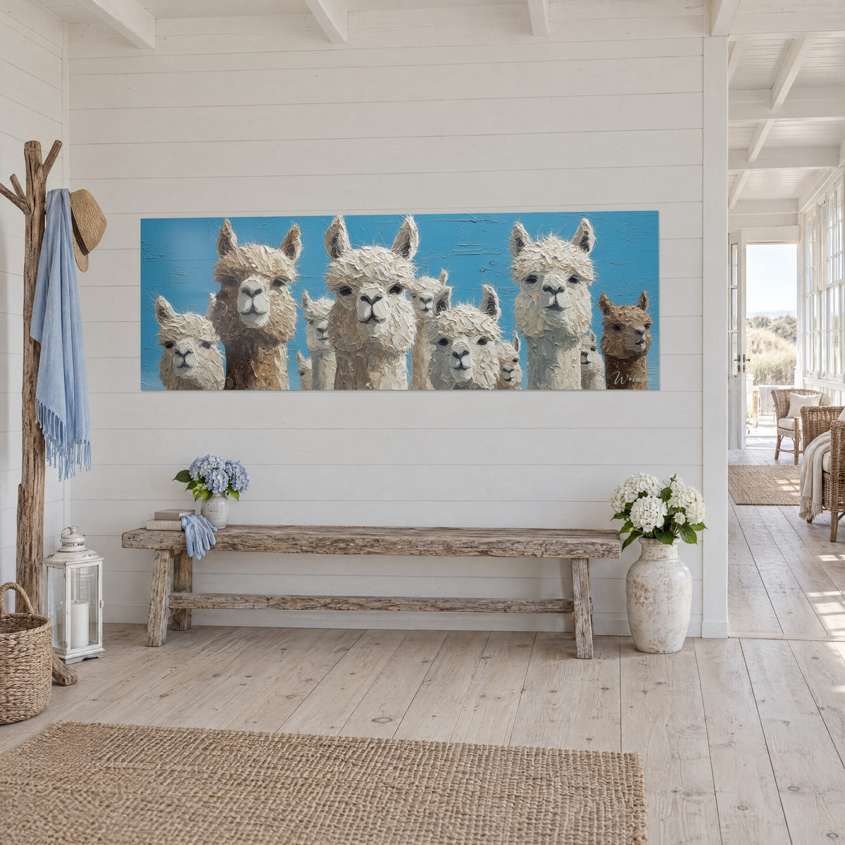 Cuadro alpacas de hocicos grises y vellón blanco y espeso, fondo azul celeste, colgado en una entrada luminosa de casa