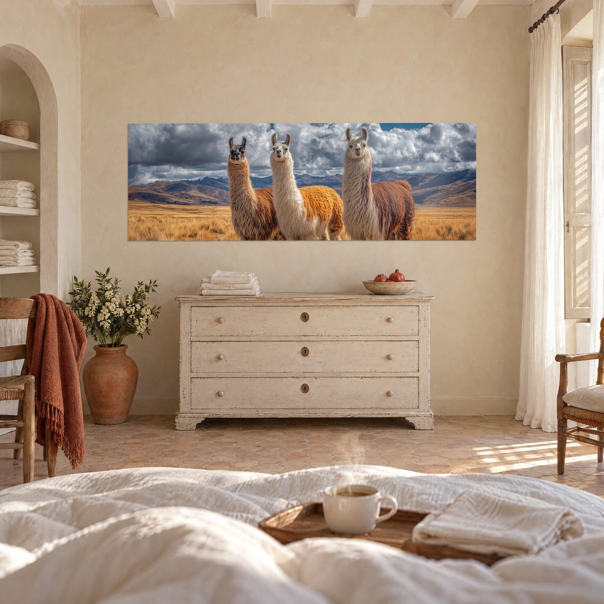 Cuadro tres llamas centinela, lana blanca y naranja vivo, montañas azuladas, sobre una cama en un dormitorio claro