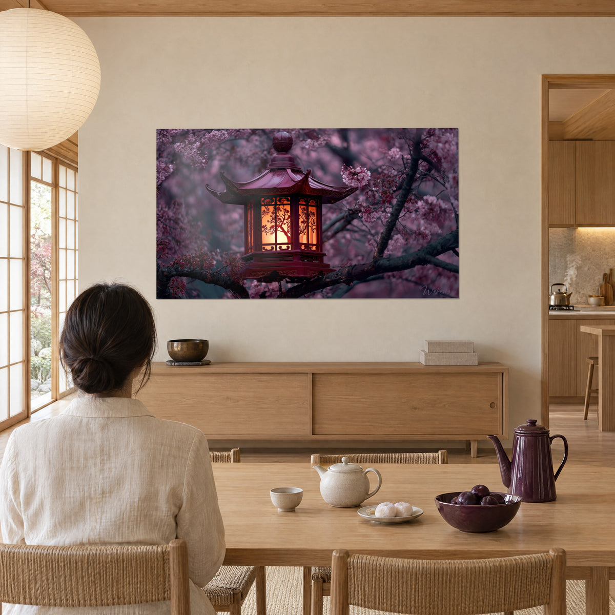 Quadro di una lanterna in legno laccato granata con sagome di alberi arancioni su sfondo rosa cipria, di fronte a un tavolo in rovere