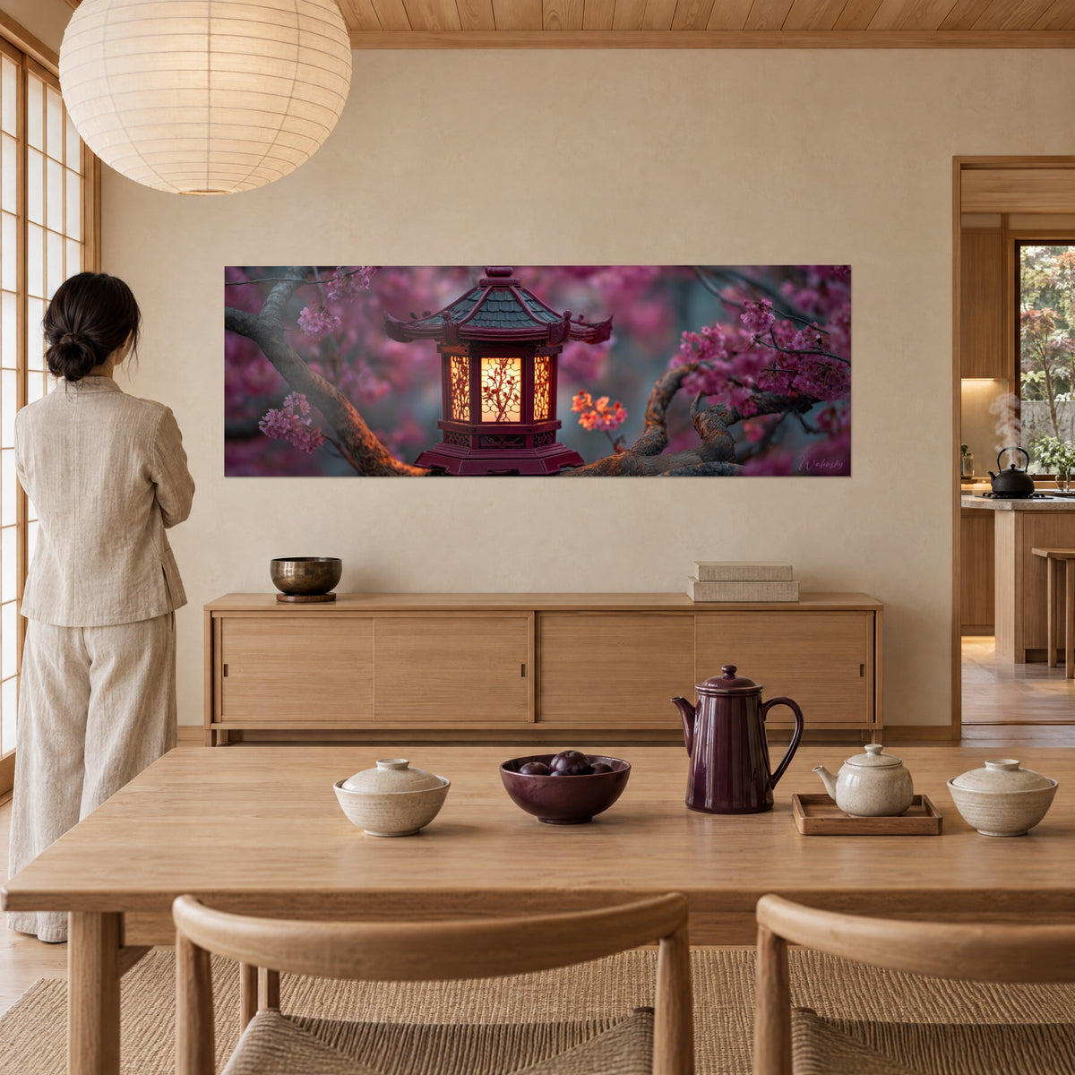 Quadro di una lanterna di legno porpora con tagli dorati e petali fucsia sfocati, una donna di spalle ammira l'opera dal tavolo da pranzo