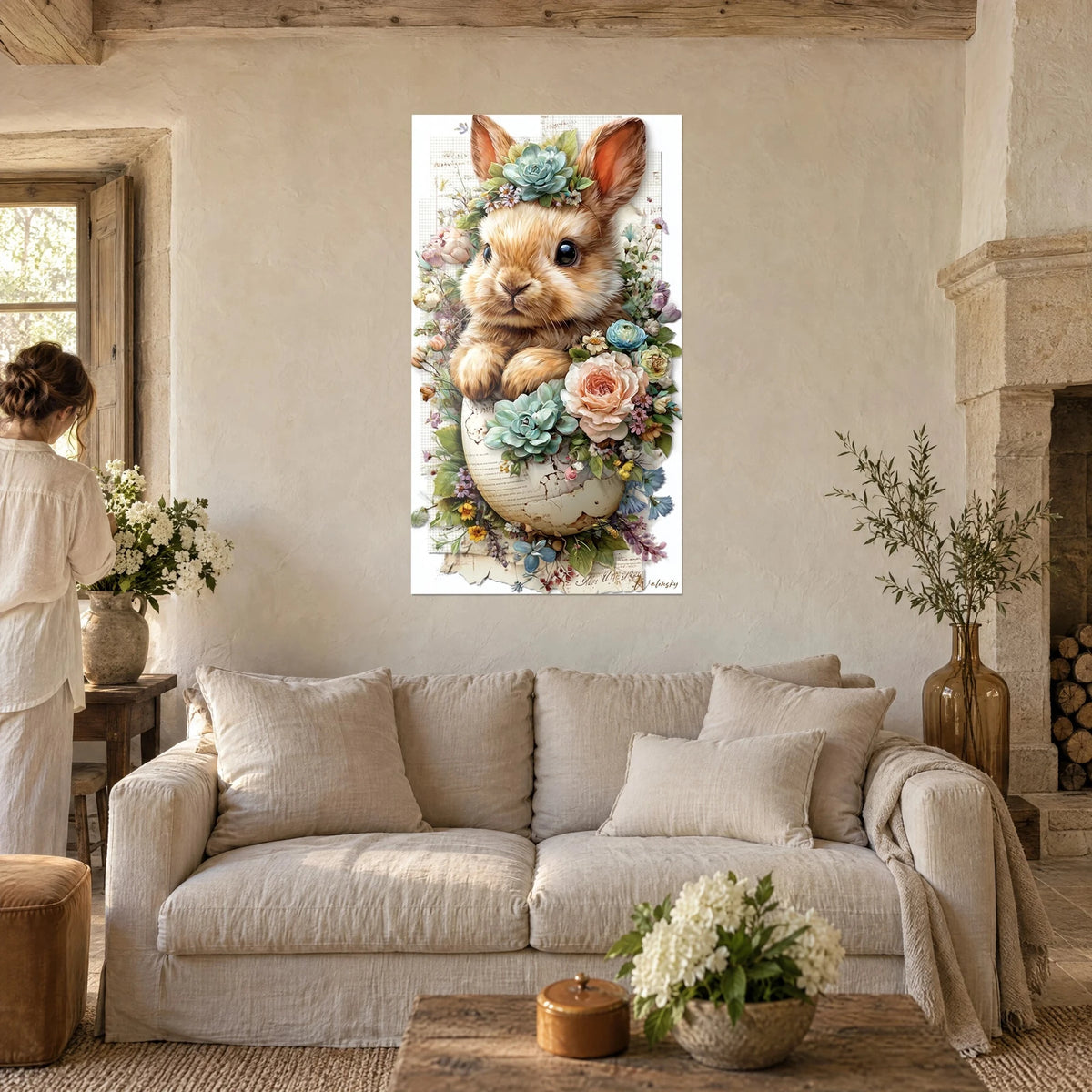 Wall art of a brown baby rabbit in a cracked eggshell, peach roses and aqua succulents, above a sofa in a bright living room