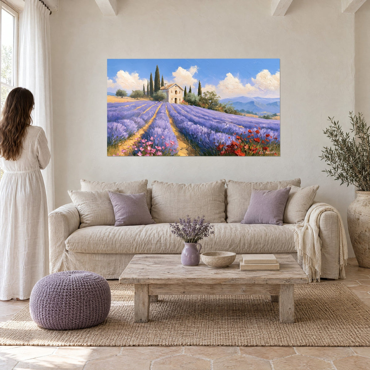 Cuadro campo de lavanda morada ondulando hacia una masía de piedra dorada y cipreses, cielo azul, mujer de espaldas, sobre un sofá en un salón luminoso