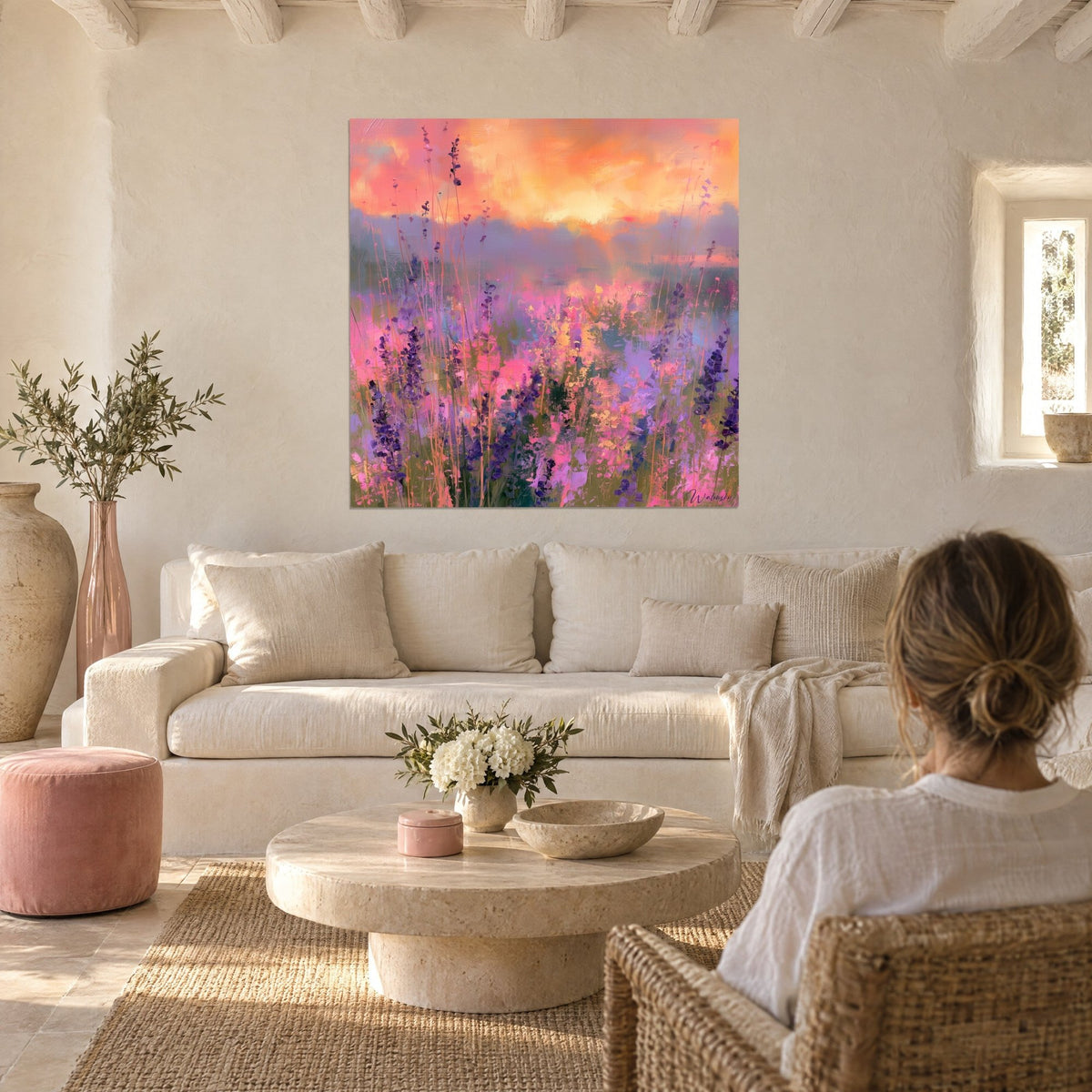 Wall art lavender field under an orange sky, purple spikes and pink touches, woman seen from behind above a sofa in a bright living room