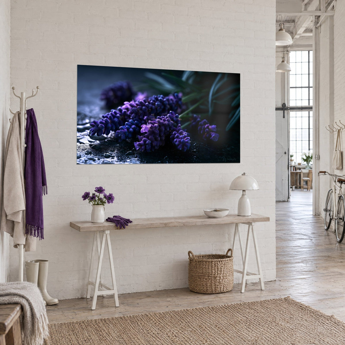 Cuadro flores de lavanda malva e índigo brillante sobre piedra negra mojada, colgado en una pared blanca de loft de artista