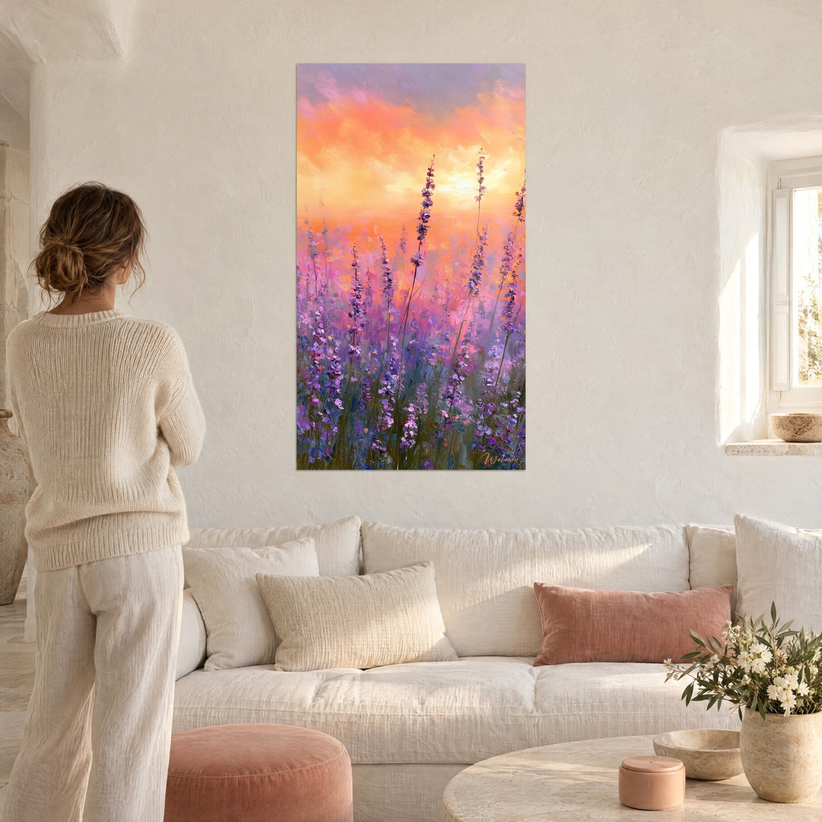 Quadro spighe di lavanda viola sotto un cielo arancio e rosa, donna di spalle, sopra un divano in un soggiorno luminoso