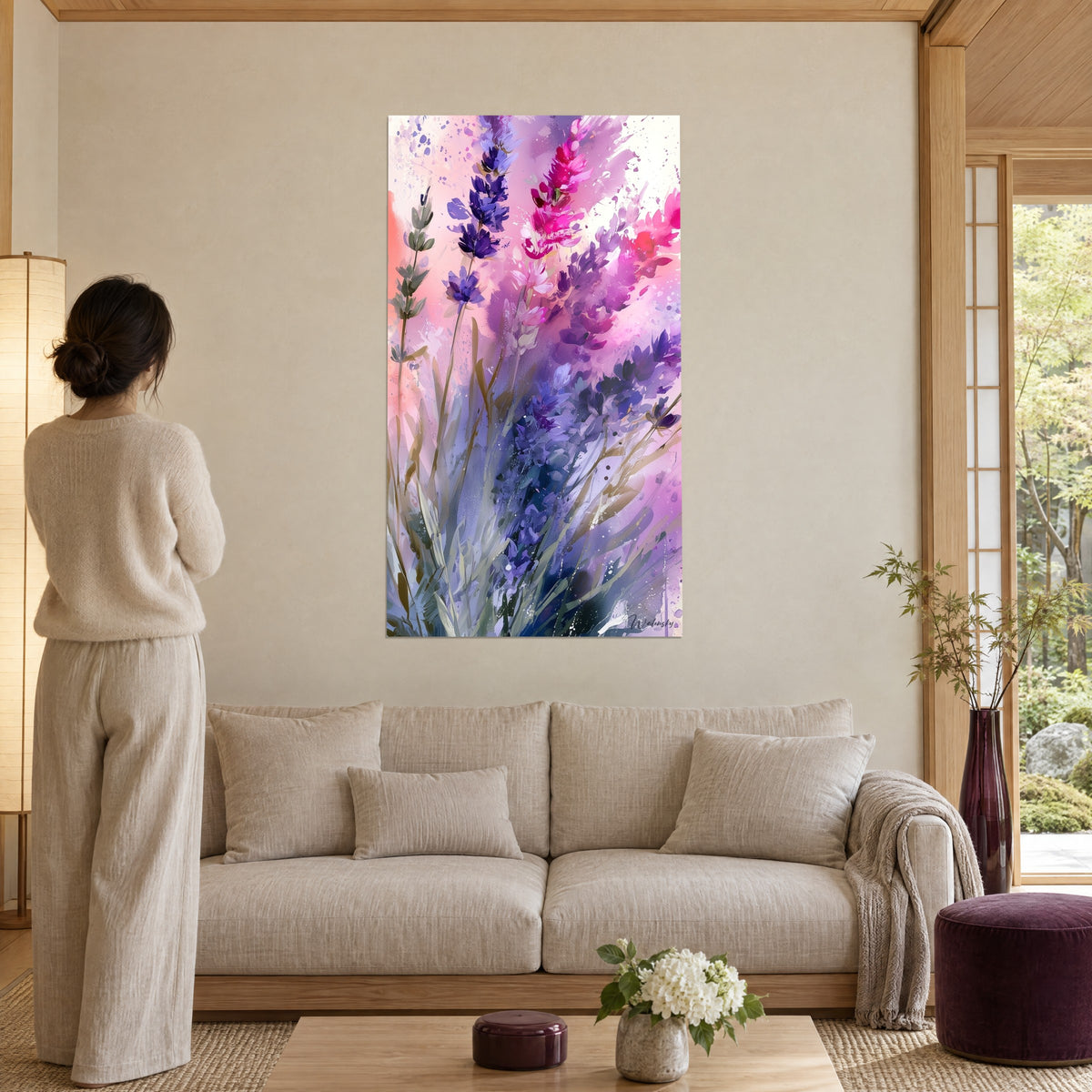 Wall art with splashed violet and fuchsia lavender spikes on a pale pink background, above a sofa in a bright living room