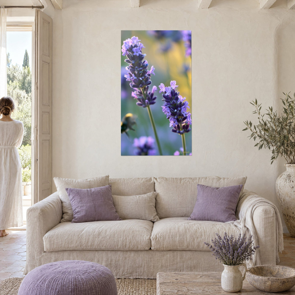 Gemälde Lavendelähren in Violett vor verschwommenem goldenem Hintergrund, Frau von hinten, über einem Sofa in einem hellen Wohnzimmer