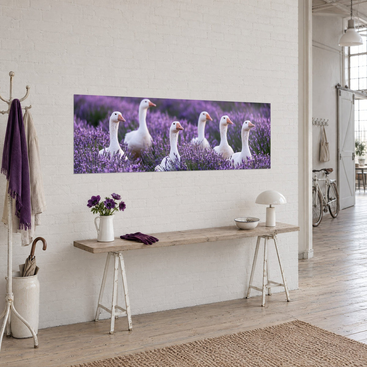 Gemälde Gänseschar mit elfenbeinfarbenen Langhälsen und korallenroten Schnäbeln zwischen Lavendelähren und Malve, Holzkonsole und weiße Ziegelwand